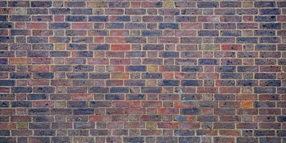 a man sitting on a bench in front of a brick wall